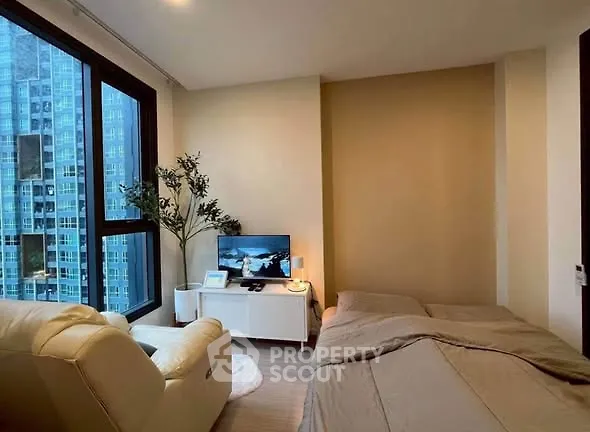 Modern bedroom with city view, cozy seating, and sleek decor
