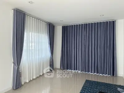 Spacious living room with elegant blue curtains and tiled flooring