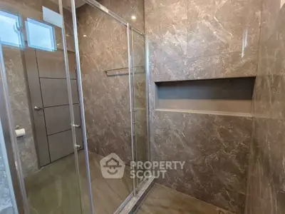 Luxurious modern bathroom with elegant marble tiles and glass shower enclosure.