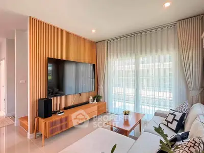 Modern living room with large TV, wooden paneling, and elegant curtains.
