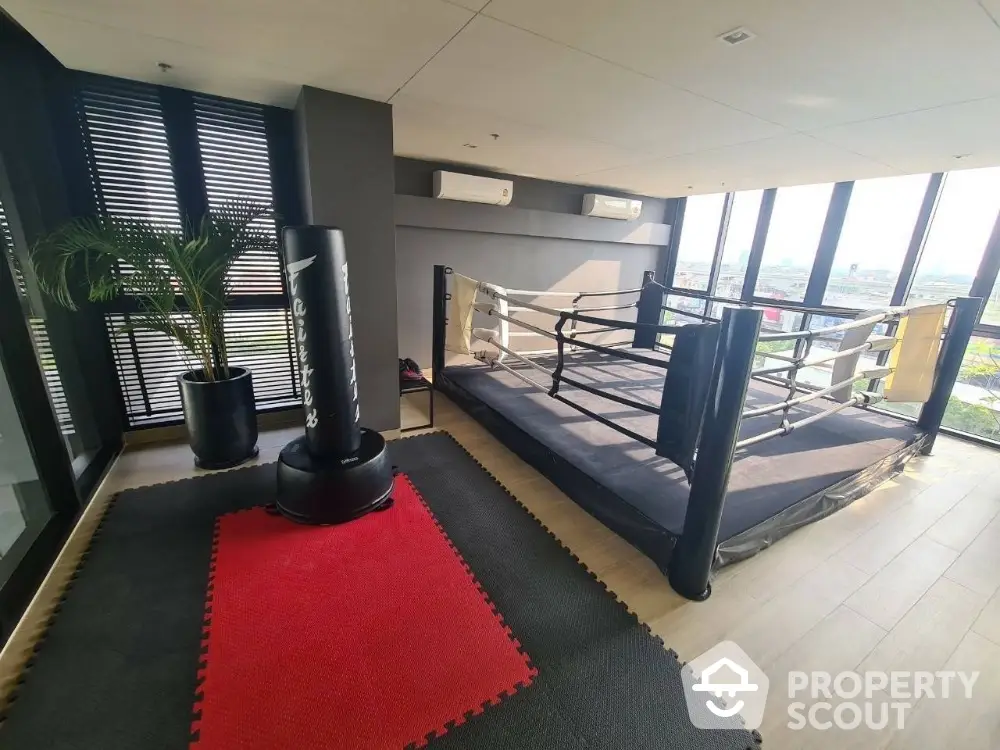 Modern gym with boxing ring and panoramic city view, perfect for fitness enthusiasts.