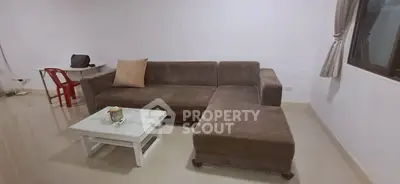 Spacious living room with modern brown sectional sofa and sleek white coffee table.