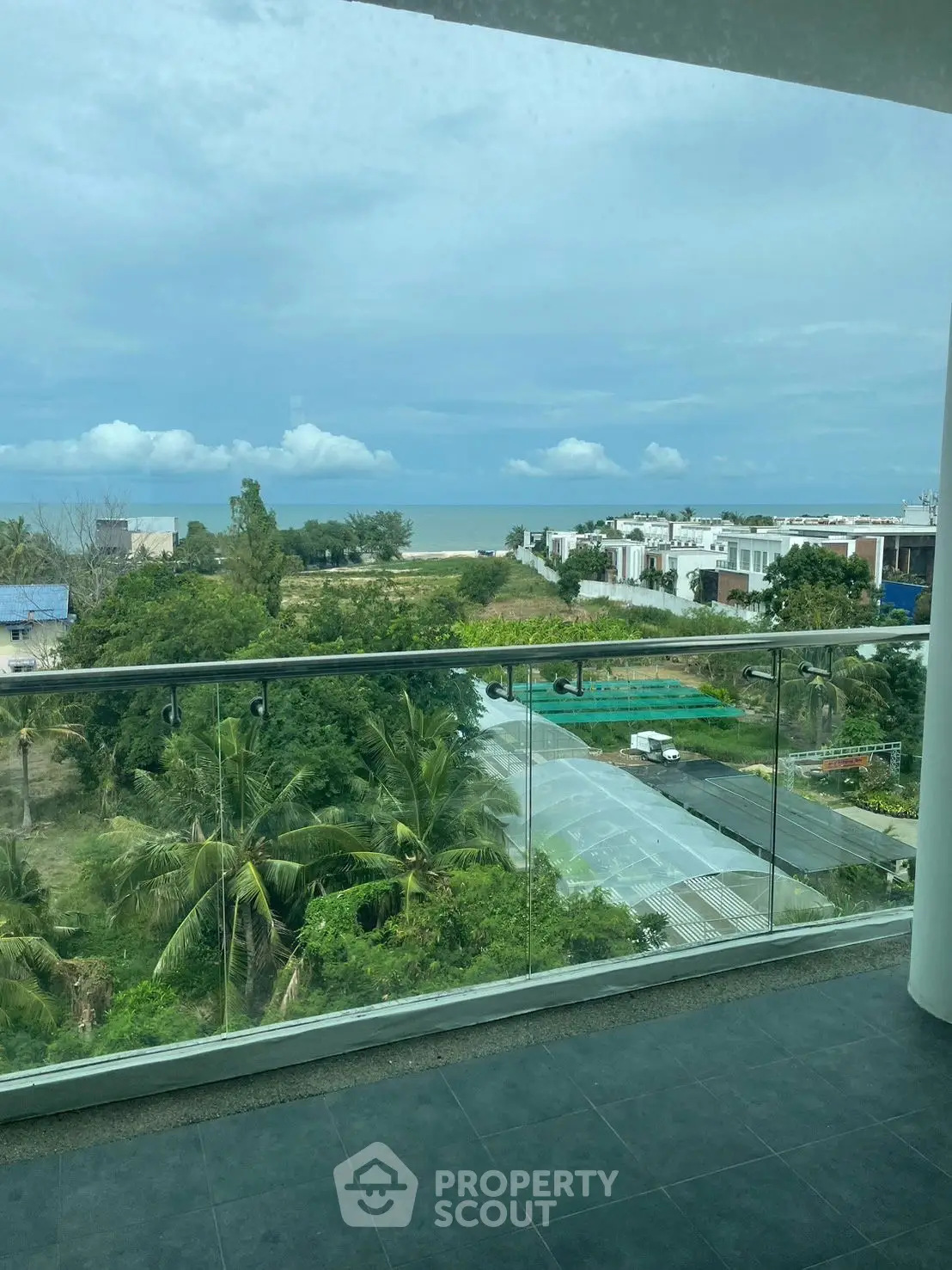 Stunning ocean view from a modern balcony with glass railing, perfect for relaxation.