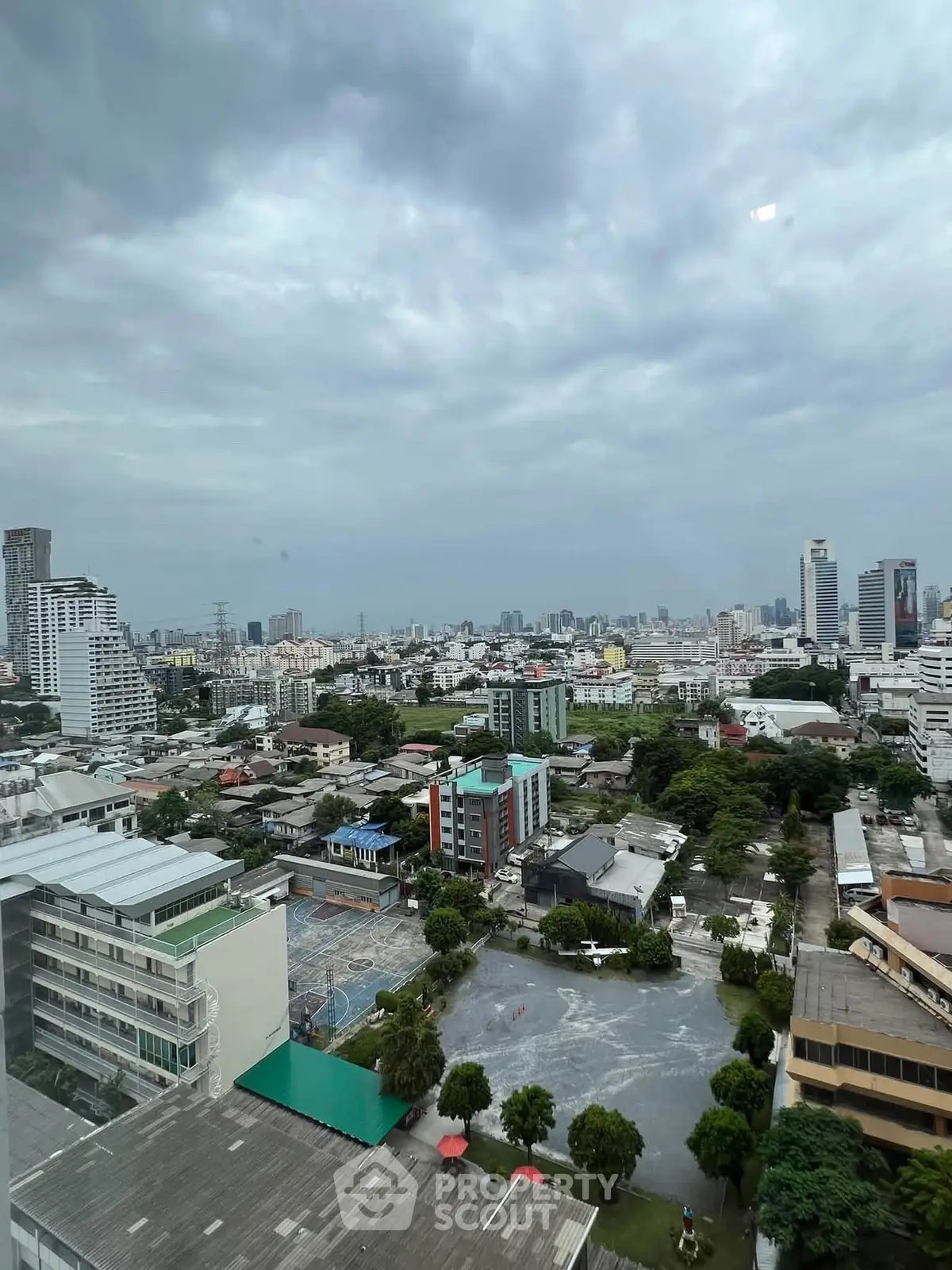 Stunning cityscape view from a high-rise building, showcasing urban skyline and lush greenery.