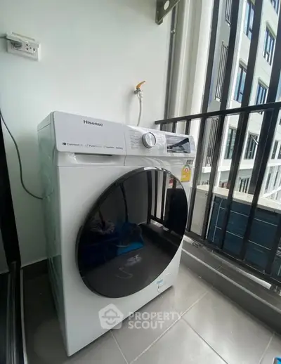 Modern washing machine on a balcony with a view of neighboring buildings.