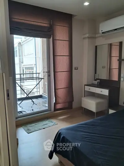 Cozy bedroom with balcony access and modern furnishings in urban apartment