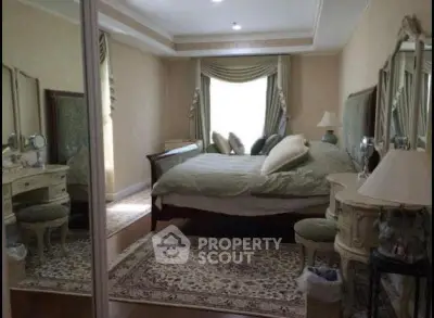 Luxurious bedroom with elegant decor and large mirror reflecting natural light.