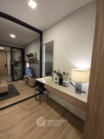 Modern apartment interior with stylish living room and study area, featuring sleek furniture and warm lighting.