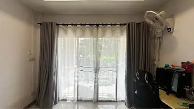 Bright living room with large sliding glass doors and curtains, featuring a desk and chair setup.