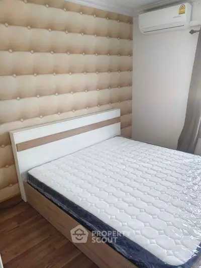 Modern bedroom with stylish padded wall and air conditioning, featuring a comfortable bed and wooden flooring.