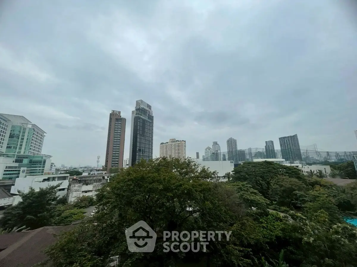 Stunning cityscape view with lush greenery and modern high-rise buildings under a cloudy sky.