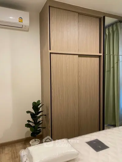 Modern bedroom with sleek wooden wardrobe and air conditioning, perfect for comfortable living.