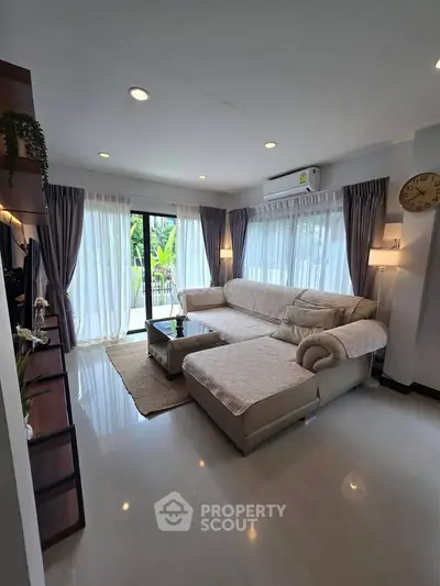 Spacious living room with large windows and modern furniture, perfect for relaxation and entertaining.