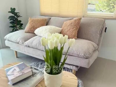 Cozy living room with plush sofa, stylish cushions, and natural light for a serene ambiance.