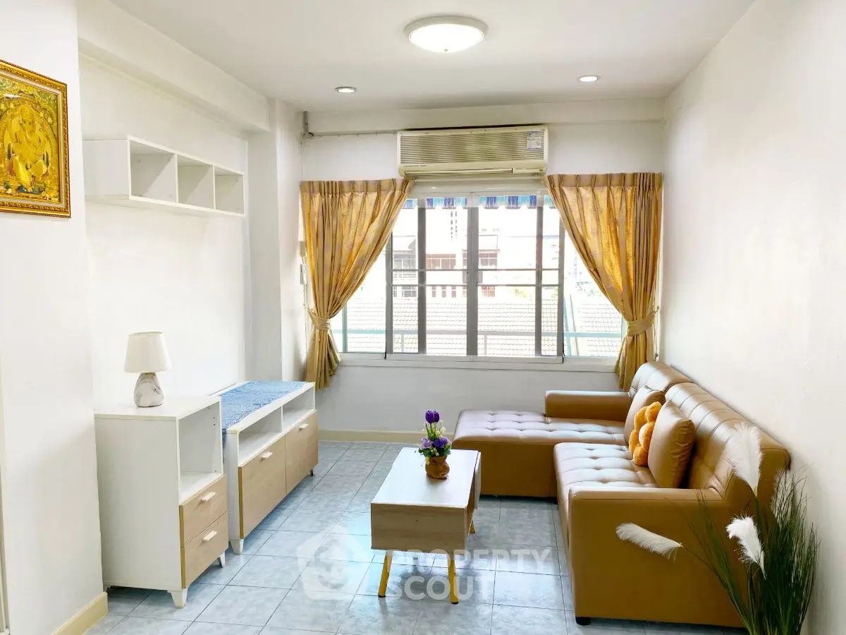Bright living room with modern furniture and large window, perfect for cozy gatherings.