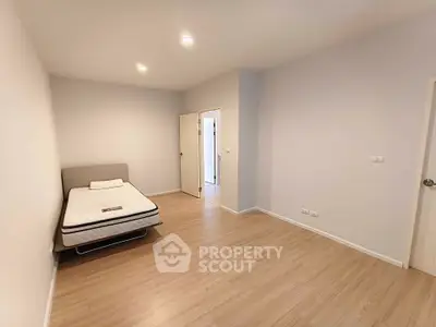 Spacious minimalist bedroom with wooden flooring and modern lighting