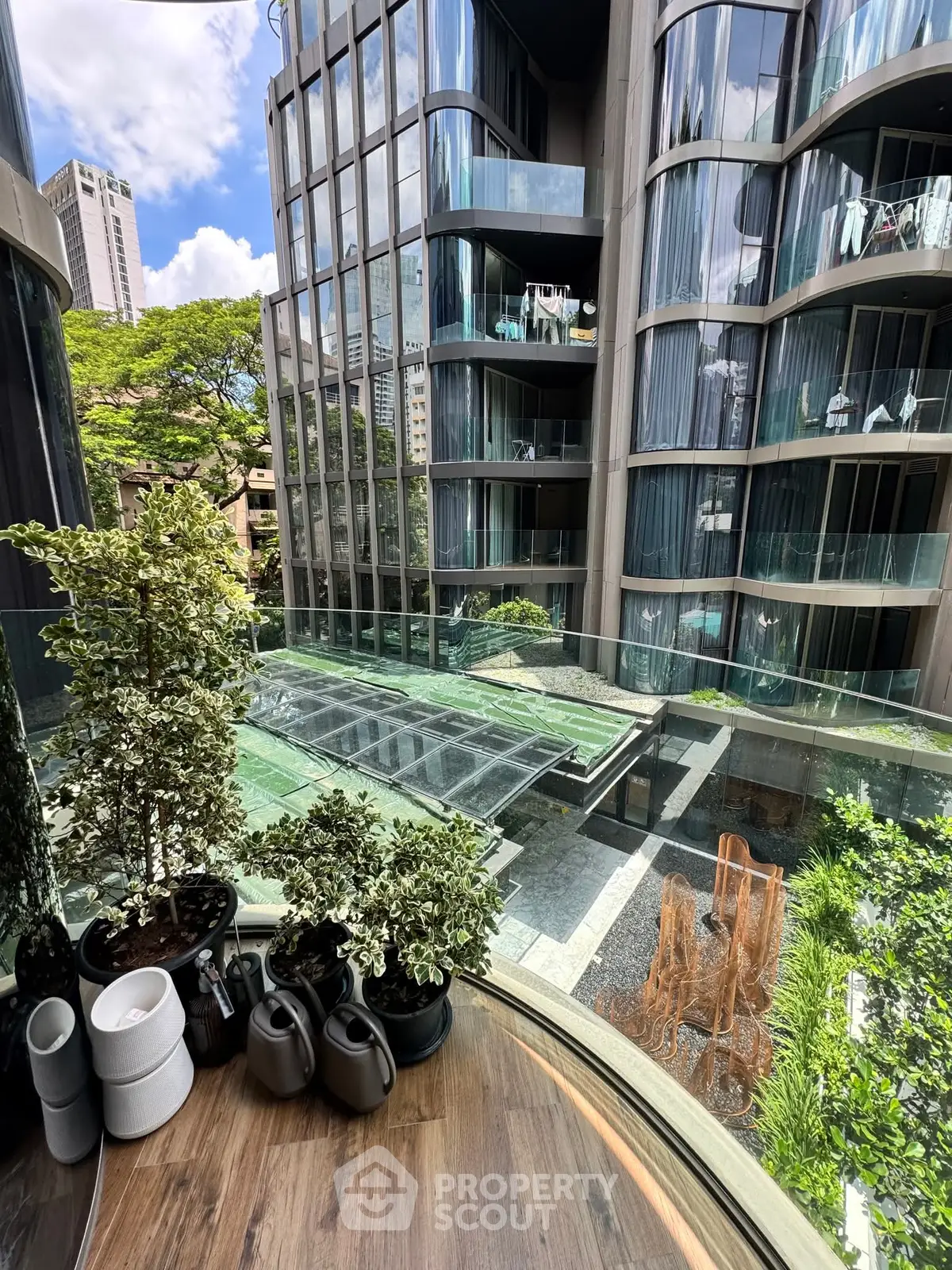 Luxurious modern apartment with curved glass facade and lush greenery view.