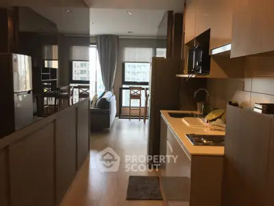 Modern open-layout kitchen and living room with natural light and stylish furnishings.