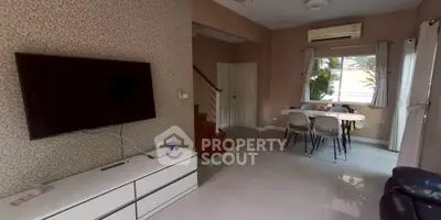 Charming living room with modern decor and dining area, featuring a wall-mounted TV and staircase.