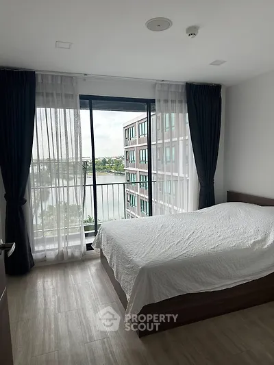Modern bedroom with large window and stunning view of cityscape and water.