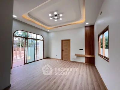 Spacious modern living room with elegant ceiling lights and large windows opening to a balcony.