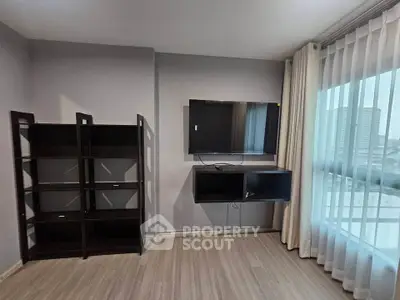 Modern living room with wall-mounted TV and large window offering city views.
