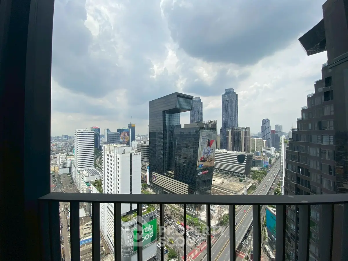 Stunning cityscape view from high-rise balcony with modern skyscrapers and cloudy sky.