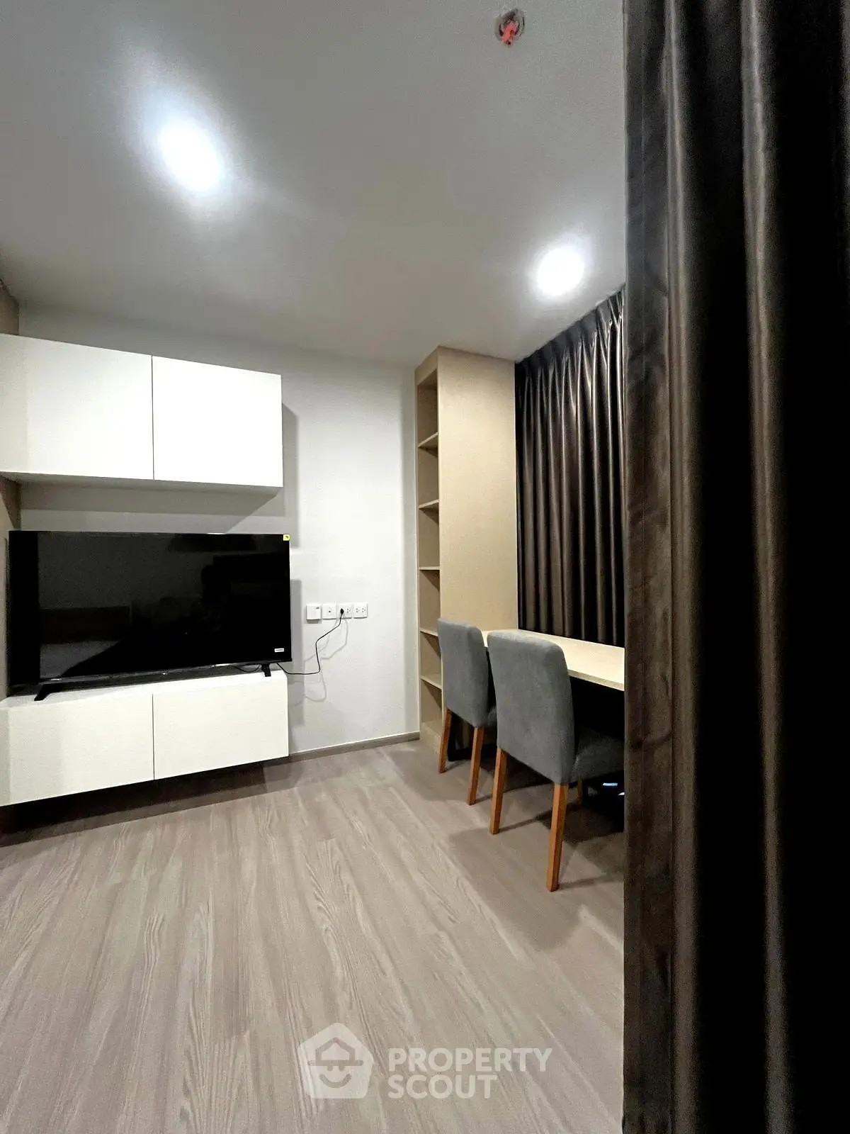 Modern living room with sleek TV setup and cozy study area, perfect for urban living.