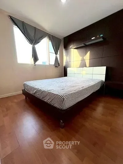 Spacious bedroom with wooden flooring and large windows for natural light.