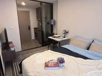 Cozy bedroom with modern decor and small kitchen area, perfect for urban living.