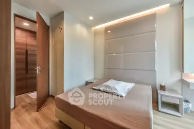 Modern bedroom with sleek design and wooden flooring, featuring a cozy bed and ambient lighting.