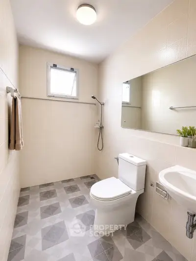 Modern bathroom with sleek design, featuring a toilet, sink, and shower area with stylish tiles.