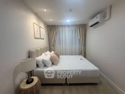 Cozy bedroom with modern decor, featuring a comfortable bed, stylish lamp, and air conditioning.