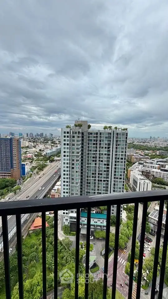 Stunning cityscape view from a high-rise balcony overlooking modern urban skyline and lush greenery.