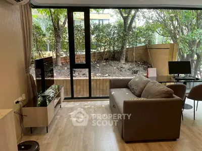 Modern living room with garden view, featuring sleek furniture and large windows for natural light.