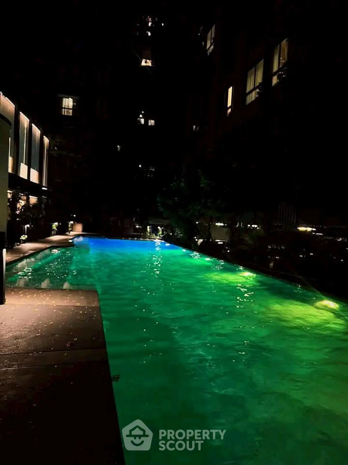 Luxurious night view of illuminated swimming pool in upscale residential complex.