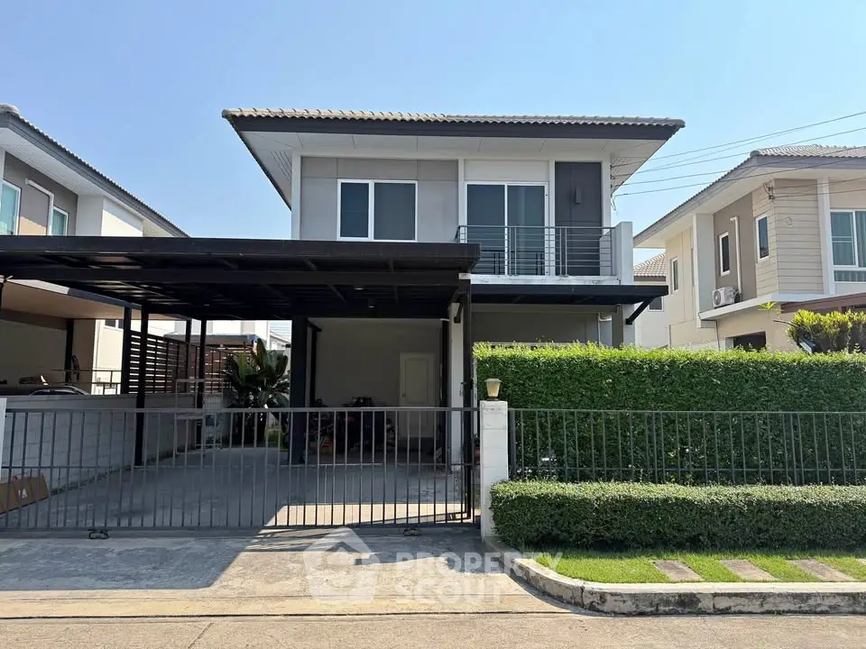 Modern two-story house with gated driveway and lush greenery