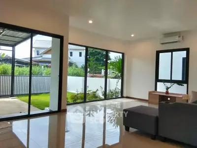 Spacious modern living room with large windows and garden view, perfect for relaxation and natural light.