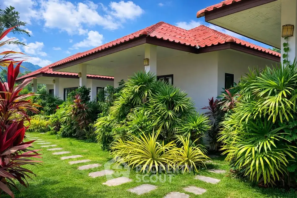 Charming tropical villa with lush garden and red-tiled roof, perfect for serene living.