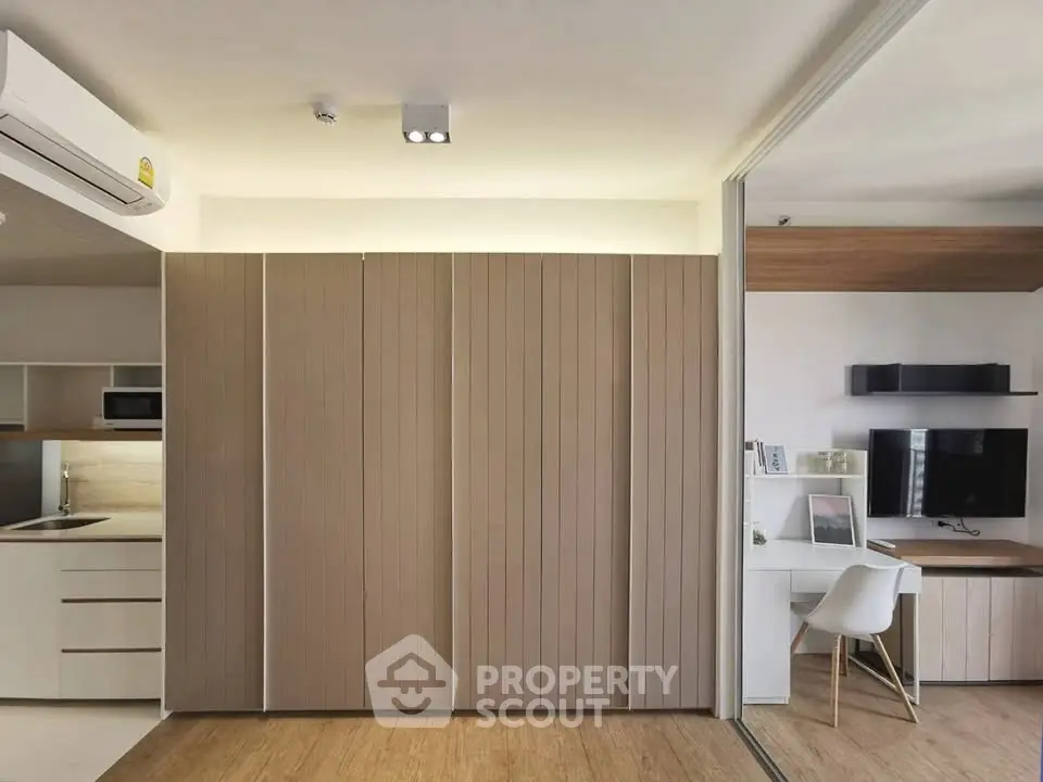 Modern apartment interior with sleek kitchen and study area, featuring minimalist design and wooden accents.