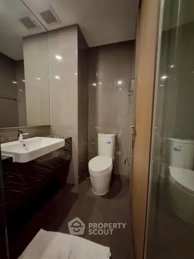 Modern bathroom with sleek fixtures and elegant design, featuring a spacious shower and contemporary sink.