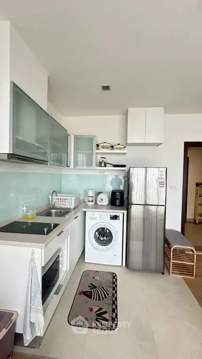 Modern kitchen with stainless steel appliances and washing machine in a compact layout.