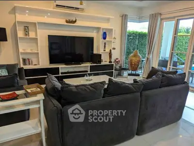 Spacious living room with modern decor and large TV, perfect for relaxation and entertainment.