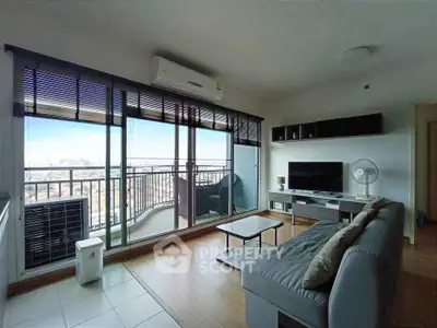 Modern living room with large balcony and city view, featuring sleek furniture and natural light.