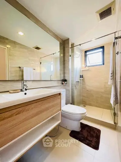 Modern bathroom with sleek wooden vanity and glass shower enclosure