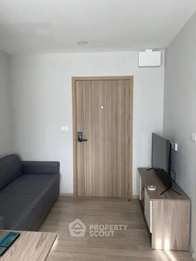 Modern living room with sleek furniture and wooden flooring, featuring a cozy sofa and flat-screen TV.