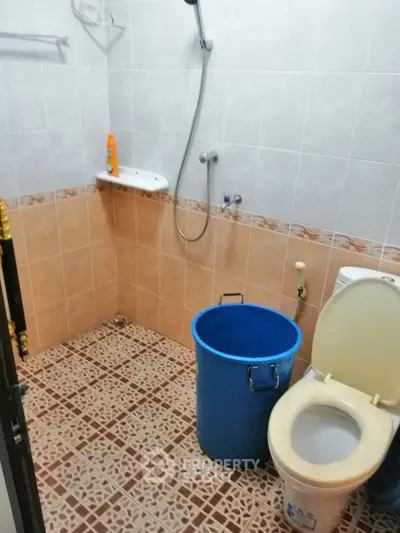 Compact bathroom with shower and toilet, featuring tiled walls and floor, ideal for efficient space use.