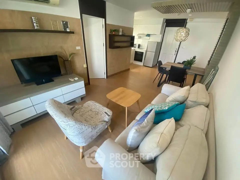 Modern living room with open kitchen, stylish decor, and cozy seating area.