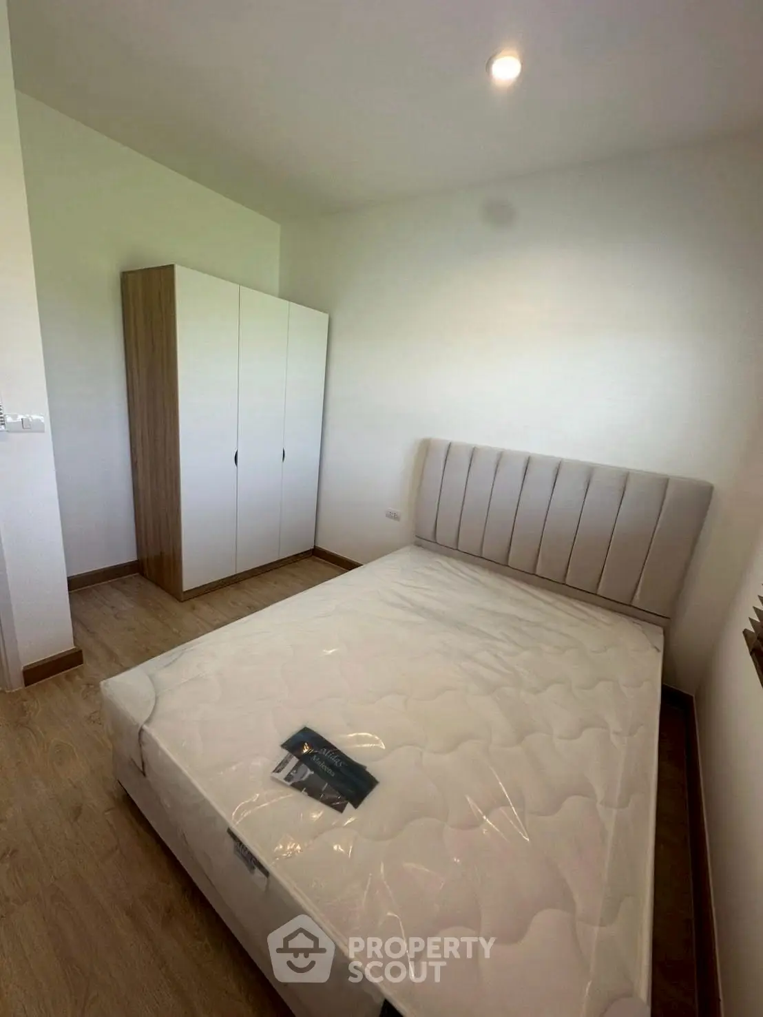 Modern bedroom with new mattress and sleek wardrobe in minimalist design.