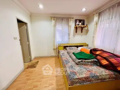 Cozy bedroom with large windows and stylish bedding in a well-lit space.